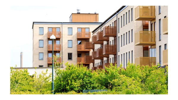 Flerbostadshus med balkonger och grönska framför