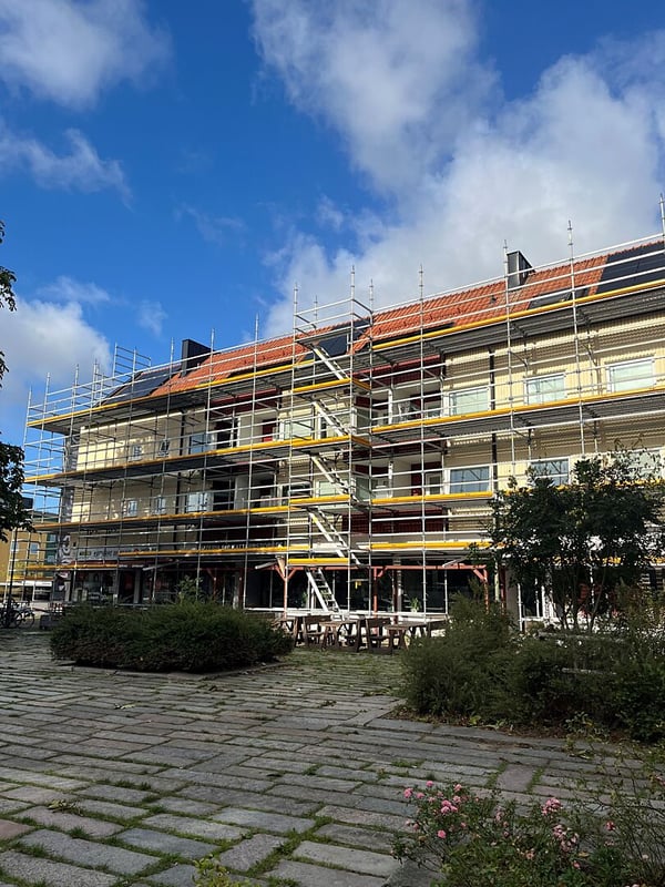 Inflyttningsklar lägenhet i hus med byggställning och tegelrött tak