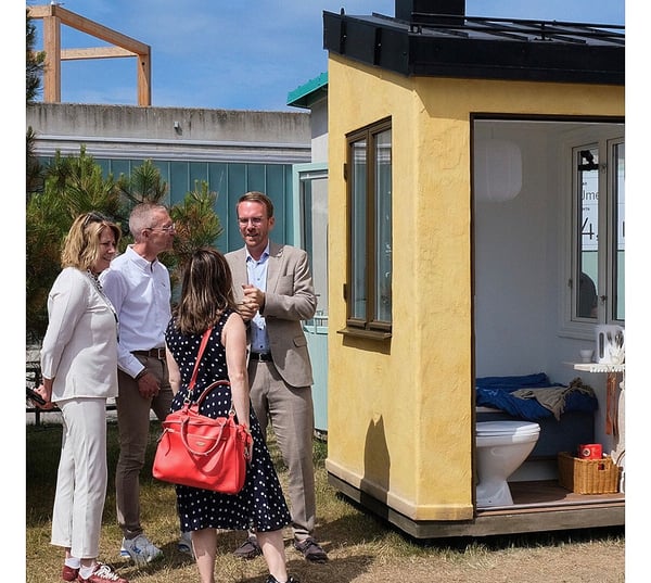 Fyra personer samtalar utanför ett gult modulhus mi Almedalen
