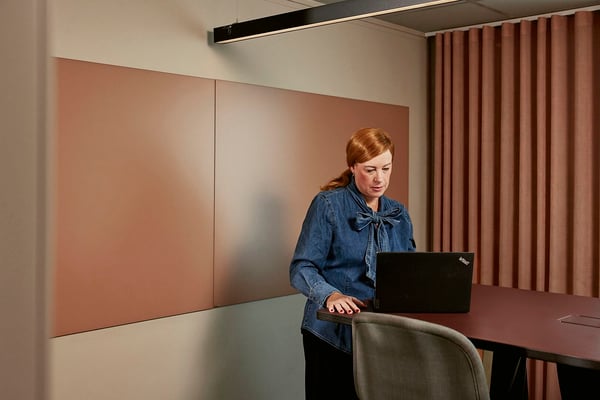 Kvinna vid konferensbord med laptop i ett modernt mötesrum