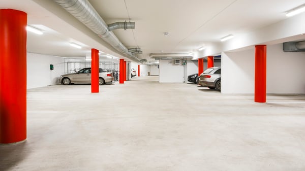 Underjordiskt garage med röda pelare och parkerade bilar