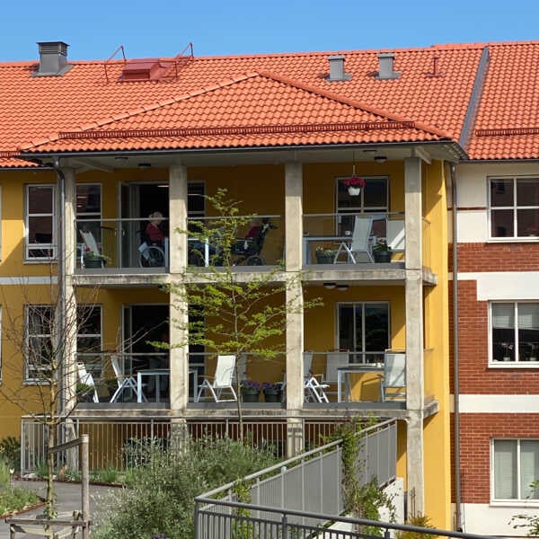 Flerfamiljshus med gul fasad, balkonger och rött tegeltak