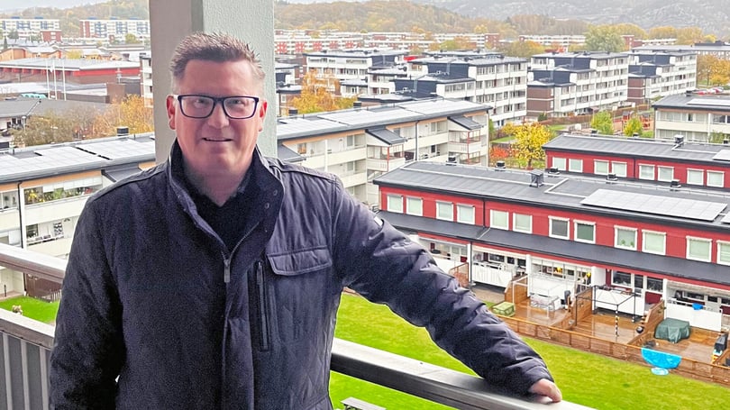 Man som står på en balkong med utsikt över hus i bakgrunden