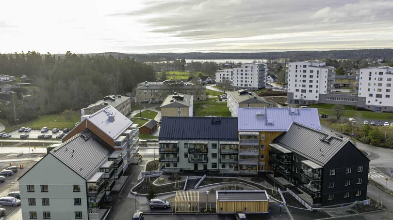 Flerbostadshus i ett bostadsområde med grönområden och parkeringsplatser i bakgrunden