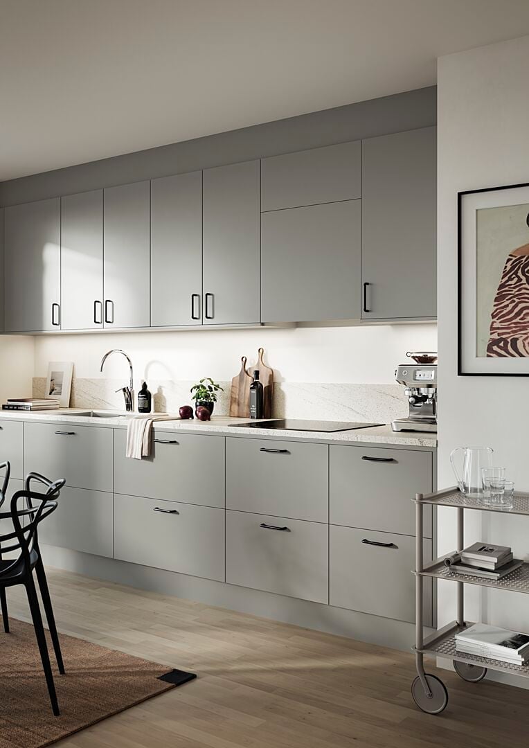 Modernt kök med grå skåpluckor, ljusa bänkskivor, en blandare och dekorativa element som växter och tavlor