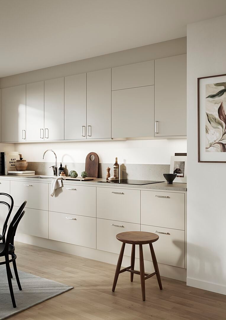 Ljust och modernt kök med vita skåp, trägolv, och minimalistisk inredning, inklusive en träpall, svart stol och väggdekoration