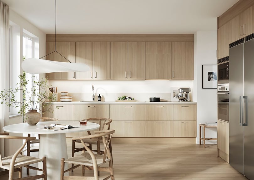 Modernt kök med ljusa träskåp, vit bänkskiva, rostfri kyl och ugn. Matplats med rund vit bordsskiva och trämöbler