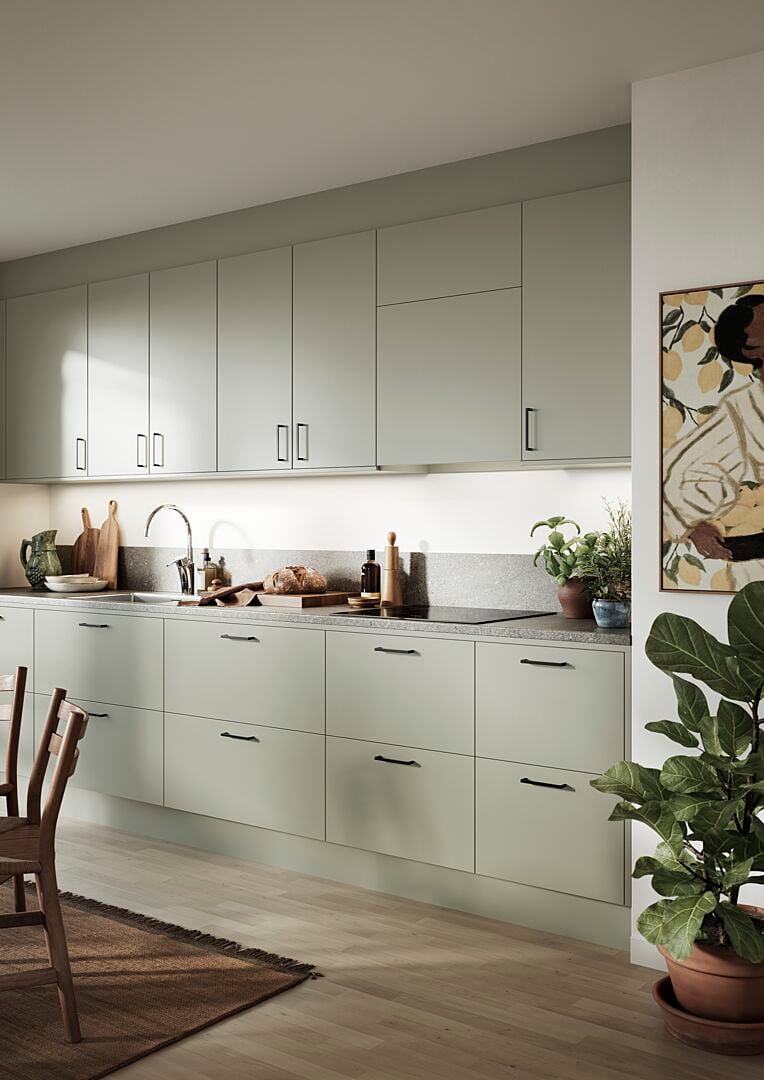 Modern kök med ljusgrå skåpluckor, växter, matlagningsdetaljer och en stol på en matta