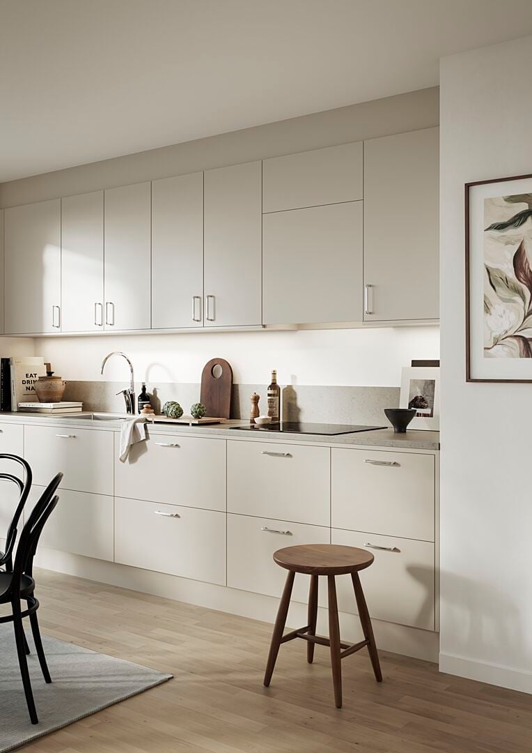 Ljust och modernt kök med vita skåp, trägolv, och minimalistisk inredning, inklusive en träpall, svart stol och väggdekoration