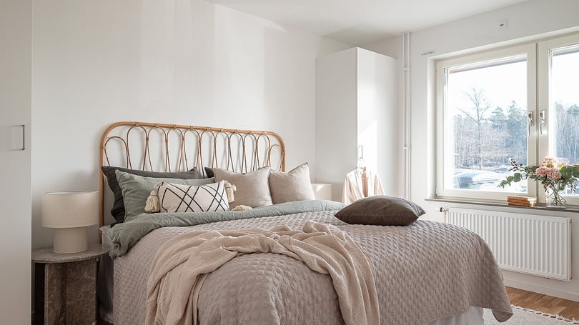 Inflyttningsklart sovrum med dubbelsäng, ljusa textilier och fönster med utsikt