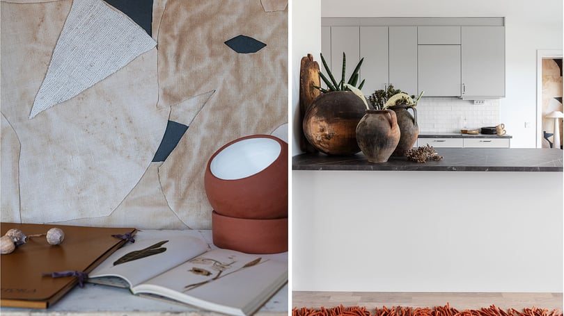 Kök med grå skåpsluckor, mörk stenbänkskiva och dekorativa vaser i förgrunden