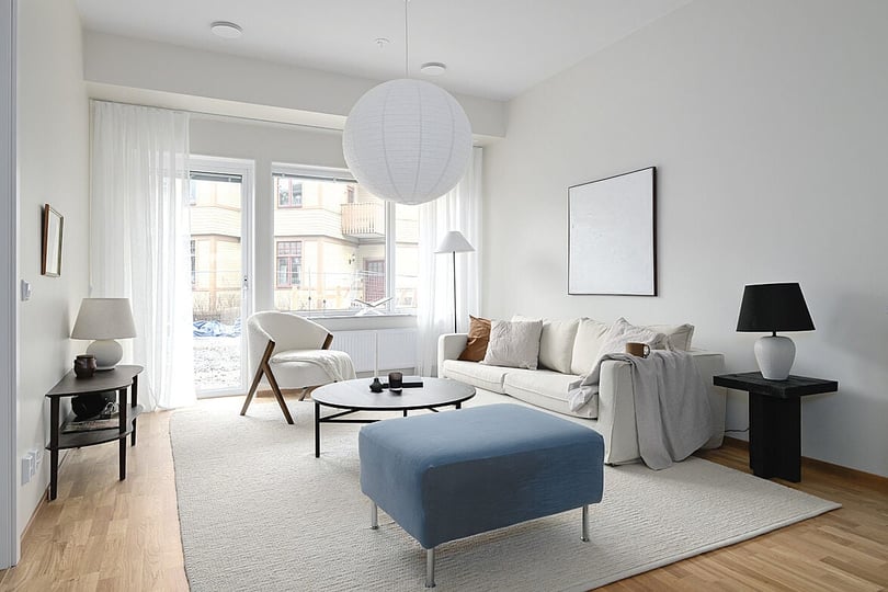 Vardagsrum med soffa, fåtölj, soffbord och ljusa textilier