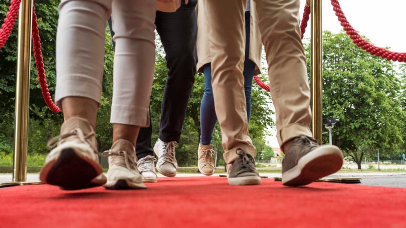 Personer som går på en röd matta utomhus, sedda från marknivå