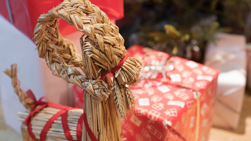 En vävd halmdekoration med röd rosett framför inslagna julklappar