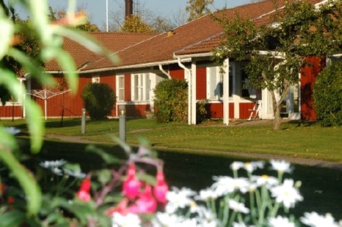 Röda bostadshus med trädgård och blomster i förgrunden