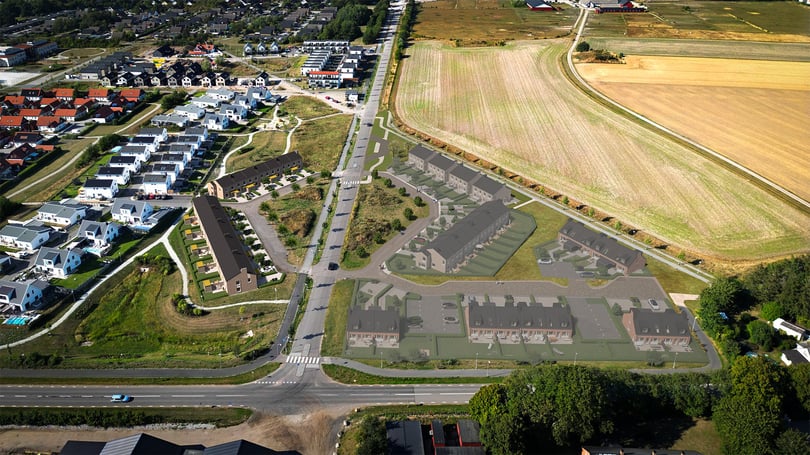 Flygfoto över ett bostadsområde med visualiserad ny bebyggelse, vägar och åkermark i anslutning