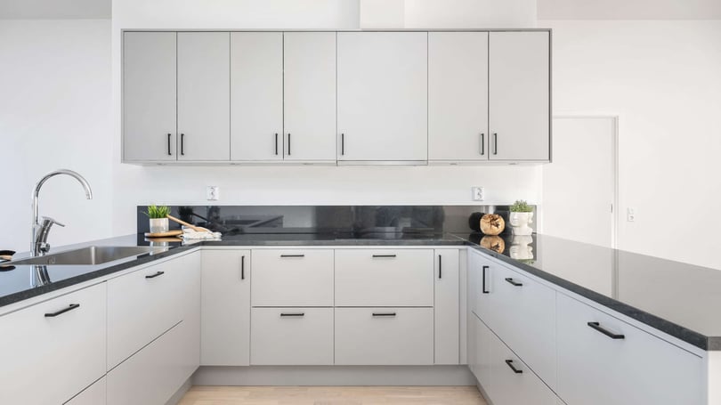 Inflyttningsklart kök med ljusa skåpluckor, svart bänkskiva och diskho