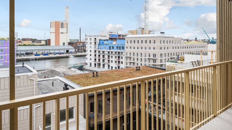 Utsikt från en balkong över Inre Hamnen i Norrköping vid vatten med byggarbetsplats och flera flerbostadshus