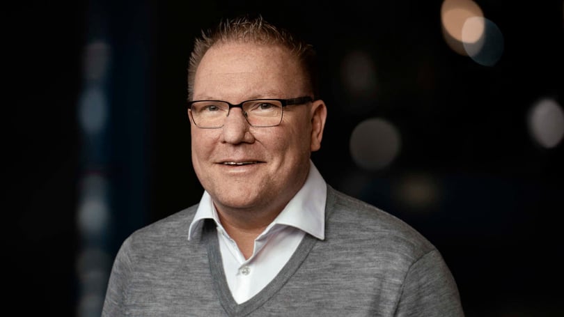 Porträtt av en man i vit skjorta och grå tröja