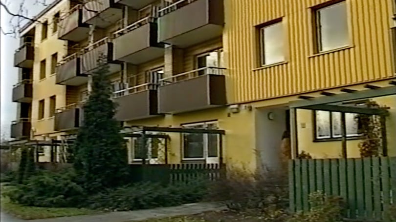 Flerbostadshus med gula fasader och balkonger samt grönskande förgård