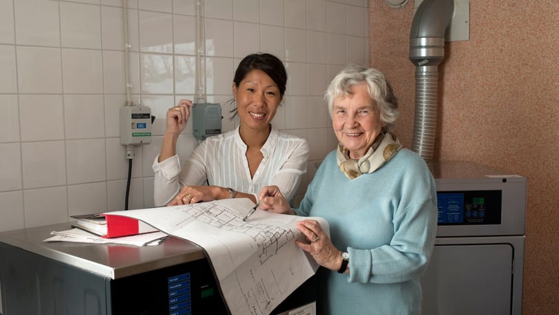 Två personer granskar byggritningar i ett teknikutrymme