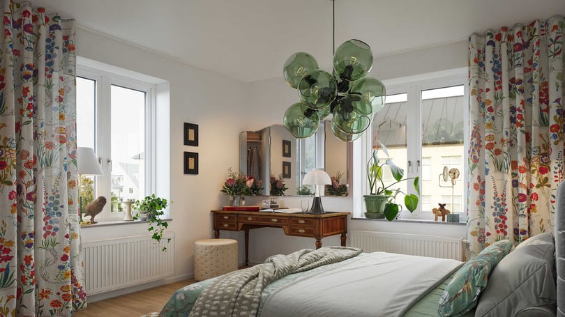 Sovrum med vita väggar, stora fönster, färgglada blommiga gardiner och en retro skrivbord med spegel. Gröna växter och en modern taklampa kompletterar inredningen