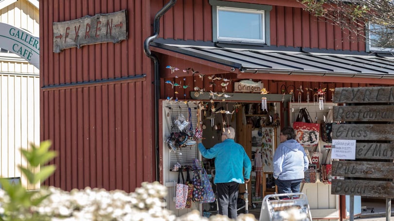 Två personer utanför en butik med skyltar och souvenirer vid entrén