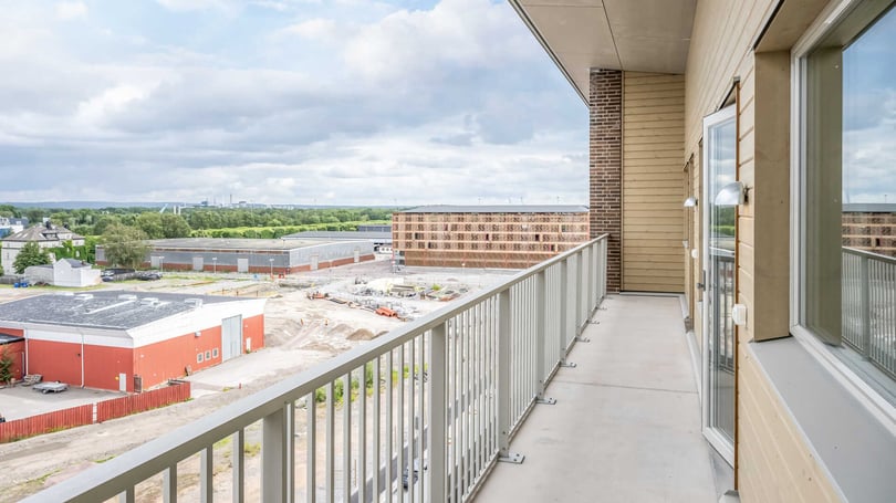 Balkong med utsikt över byggarbetsplats och bostadshus