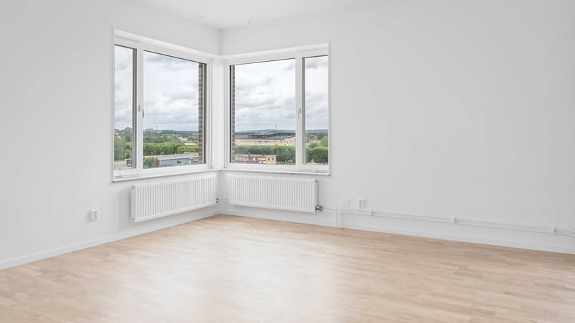 Inflyttningsklart vardagsrum med stora fönster och ljusa väggar