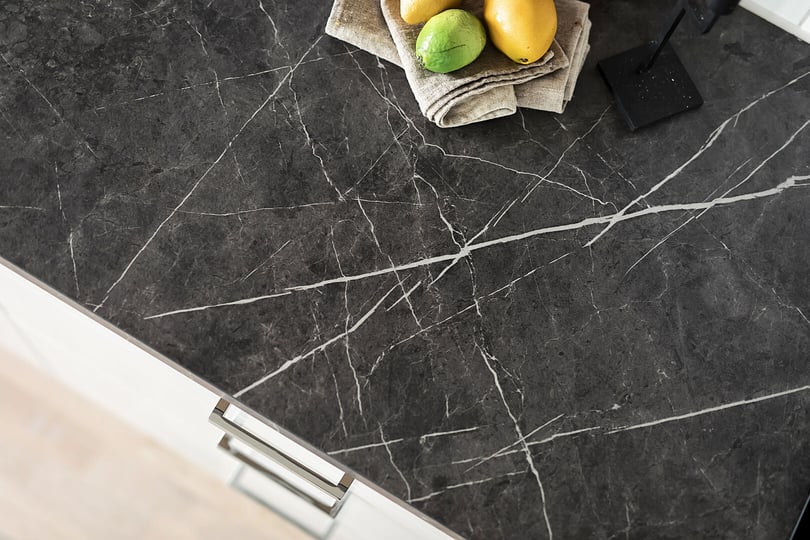 Svart marmorerad bänkskiva med skålar, citroner och en grön lime