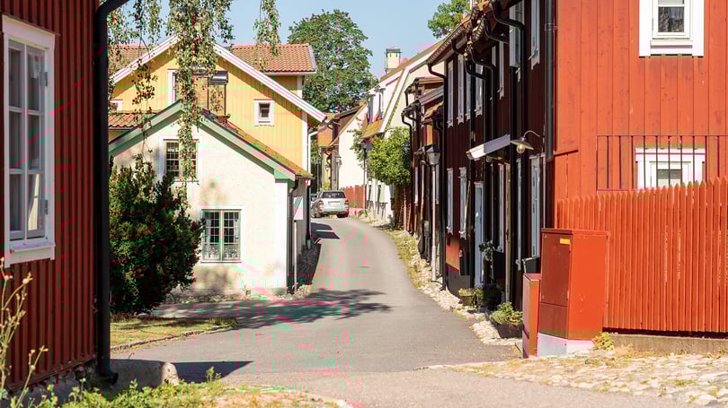 Gata i Strängnäs med färgglada trähus och en smal asfaltväg i ett bostadsområde