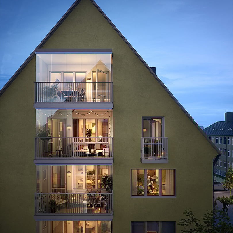 Fasad på bostadshus med flera upplysta balkonger och lägenheter i kvällsljus