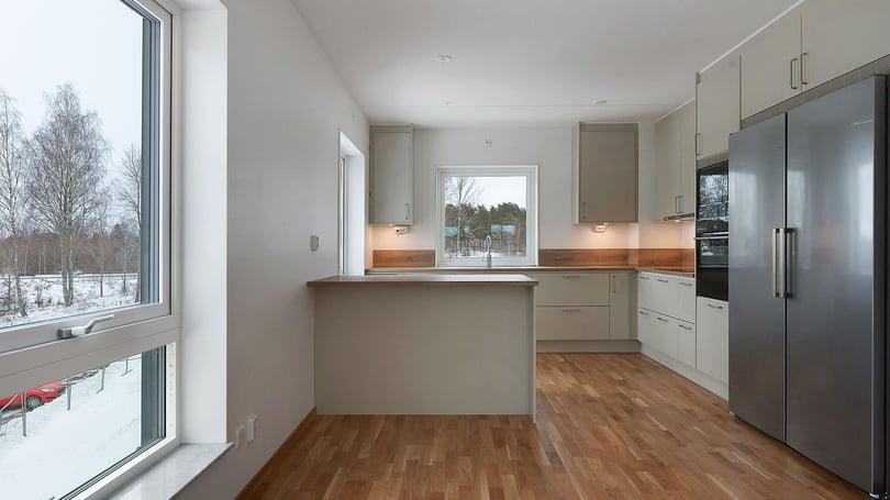 Inflyttningsklar lägenhet med modernt kök, vita skåpsluckor, träbänkskiva och rostfri kyl och frys