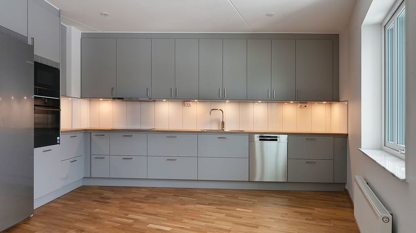 Modernt grått kök med skåp, diskho, integrerad diskmaskin och trägolv