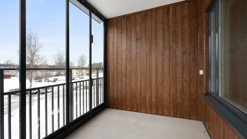 Inflyttningsklar lägenhet med inglasad balkong, träpanel och utsikt mot snötäckt gård
