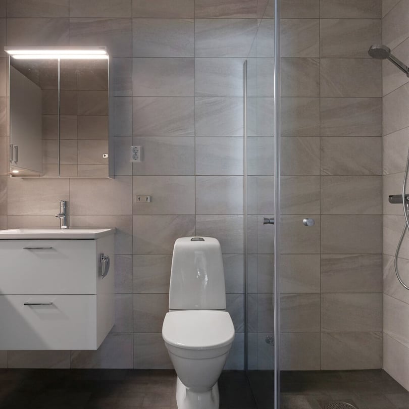 Inflyttningsklart badrum med vitt handfat, spegelskåp, toalett och duschhörna