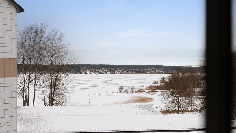 Snötäckt tomt rum med utsikt över frusen sjö och vinterlandskap