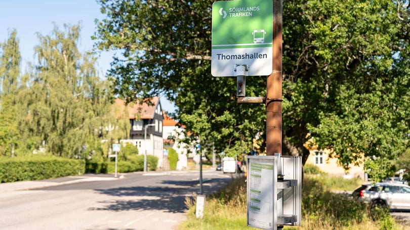 Busshållplatsen Thomashallen vid en lugn gata med träd och bostadshus