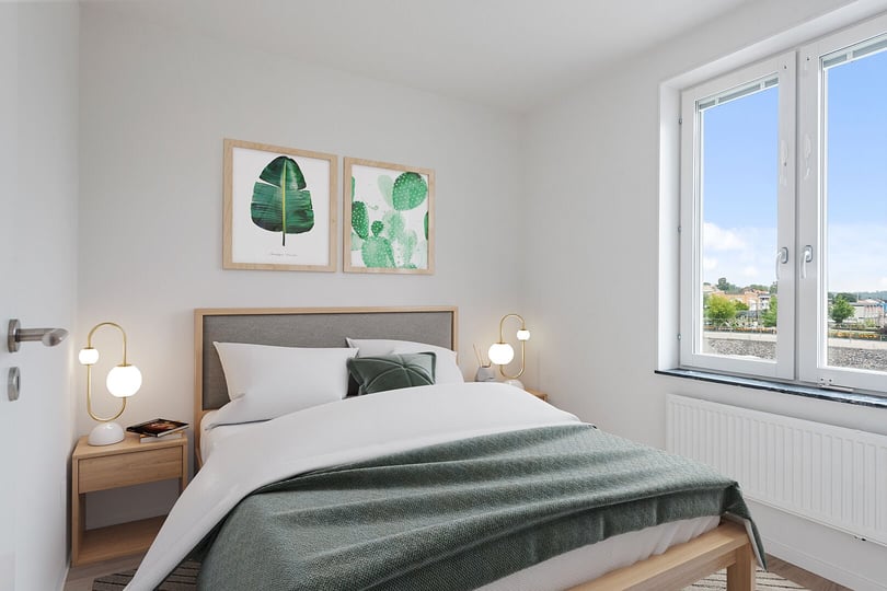Sovrum med dubbelsäng, gröna detaljer och fönster med utsikt