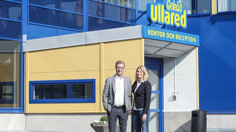 Porträtt av två personer utanför en byggnad med skylt för kontor och reception