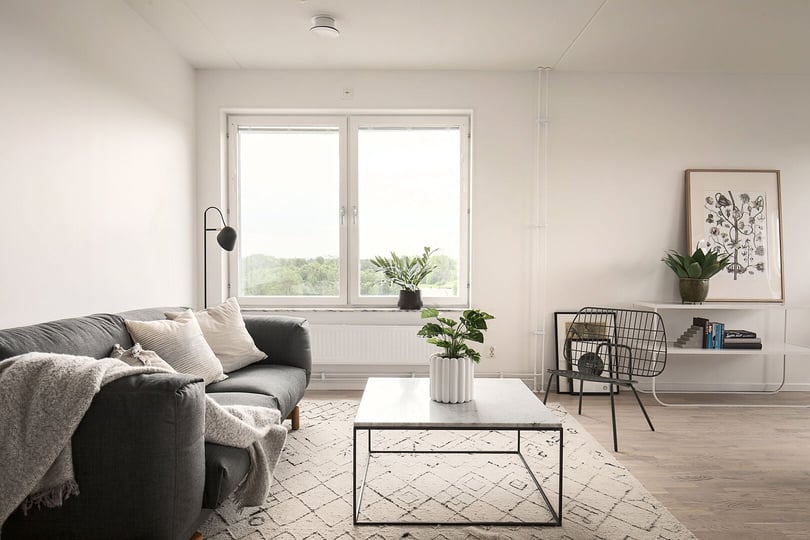 Inflyttningsklart vardagsrum med soffa, soffbord, fönster och ljusa väggar