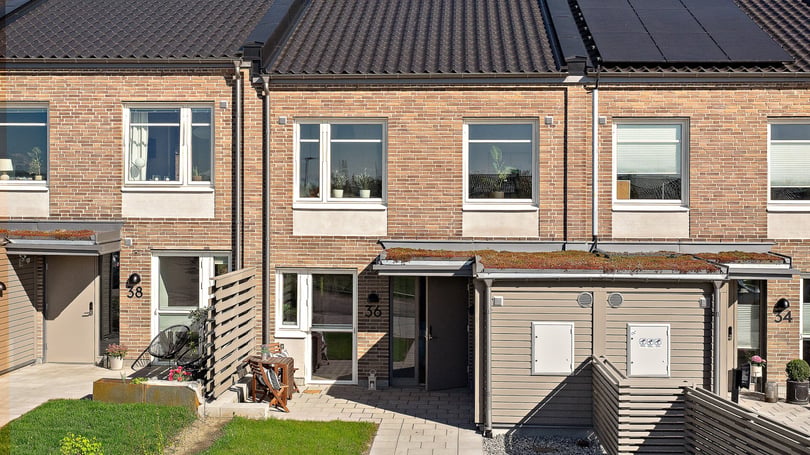 Radhus med entré, uteplats och grön trädgård i soligt väder