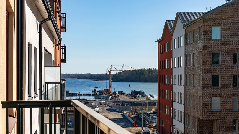 Inflyttningsklar lägenhet med balkong och utsikt mot vatten och byggarbetsplats