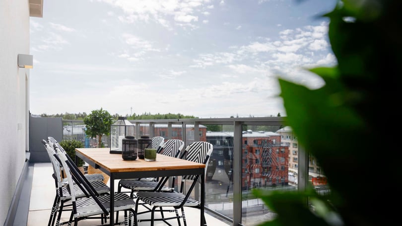 Möblerad balkong med matbord, stolar och utsikt över stadsmiljö