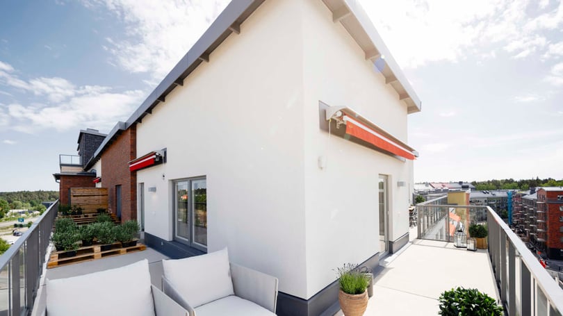 Balkong med sittgrupp och utsikt över bostadskvarter, vid ljus fasad och moderna fönster