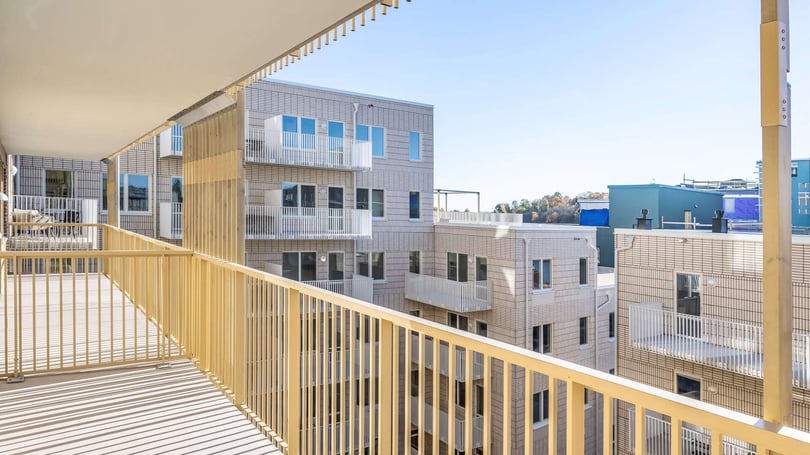 Balkong med utsikt över inflyttningsklar lägenhet och moderna flerbostadshus i ljus tegelarkitektur