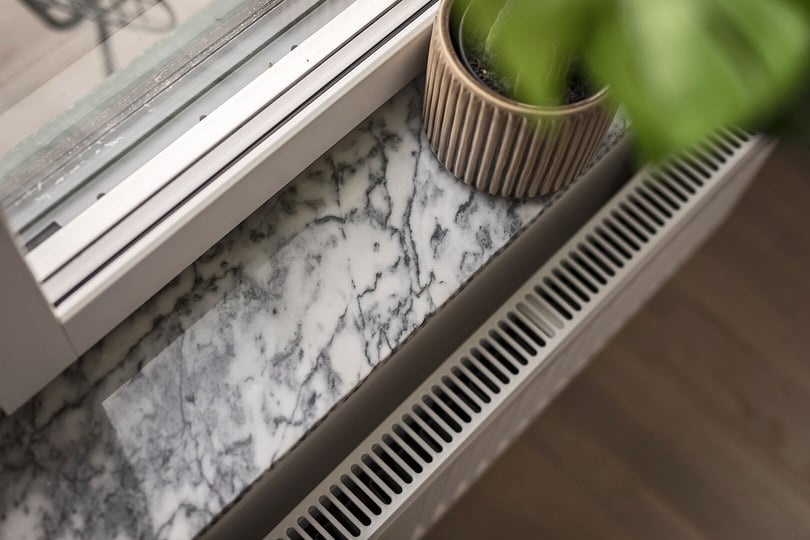 Fönsterbänk i marmor med växtkruka och element under fönstret
