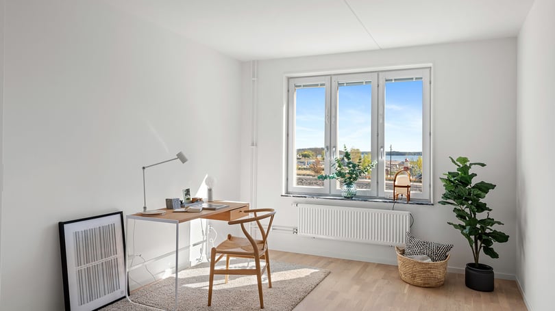 Inflyttningsklar lägenhet med ljusa väggar, stora fönster och möblerad arbetsplats i modern stil