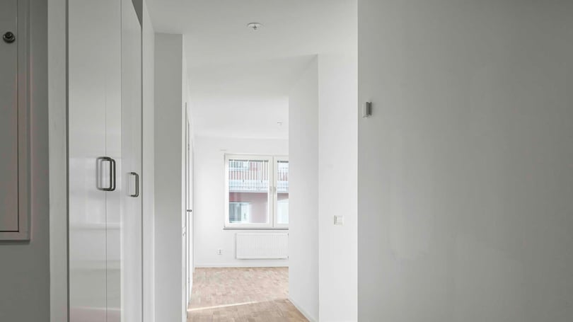 Inflyttningsklar lägenhet med ljusa väggar, trägolv och garderober i hallen
