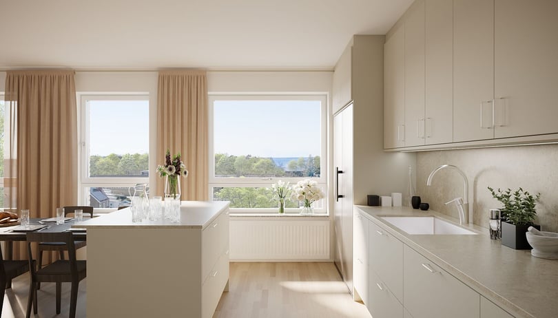 Ljust och modernt kök med vita skåp, köksö och stora fönster som släpper in naturligt ljus